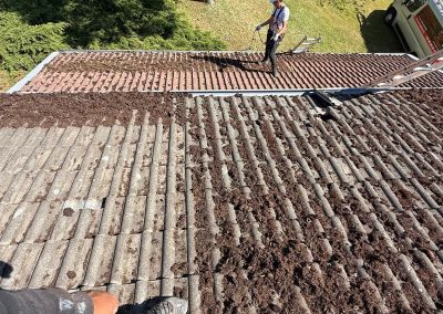 Artisan couvreur en pleine intervention de grattage et nettoyage d'une toiture très encrassée à Baume-les-Dames.