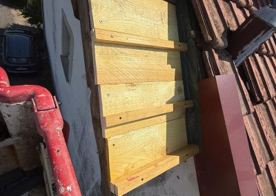 Pose minutieuse d'une nouvelle planche de rive en bois massif pour solidifier l'étanchéité et préparer la pose de la gouttière à Thise.