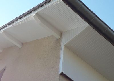 Finition impeccable d'un habillage de débord de toit en PVC blanc avec pose de gouttière à Thise.